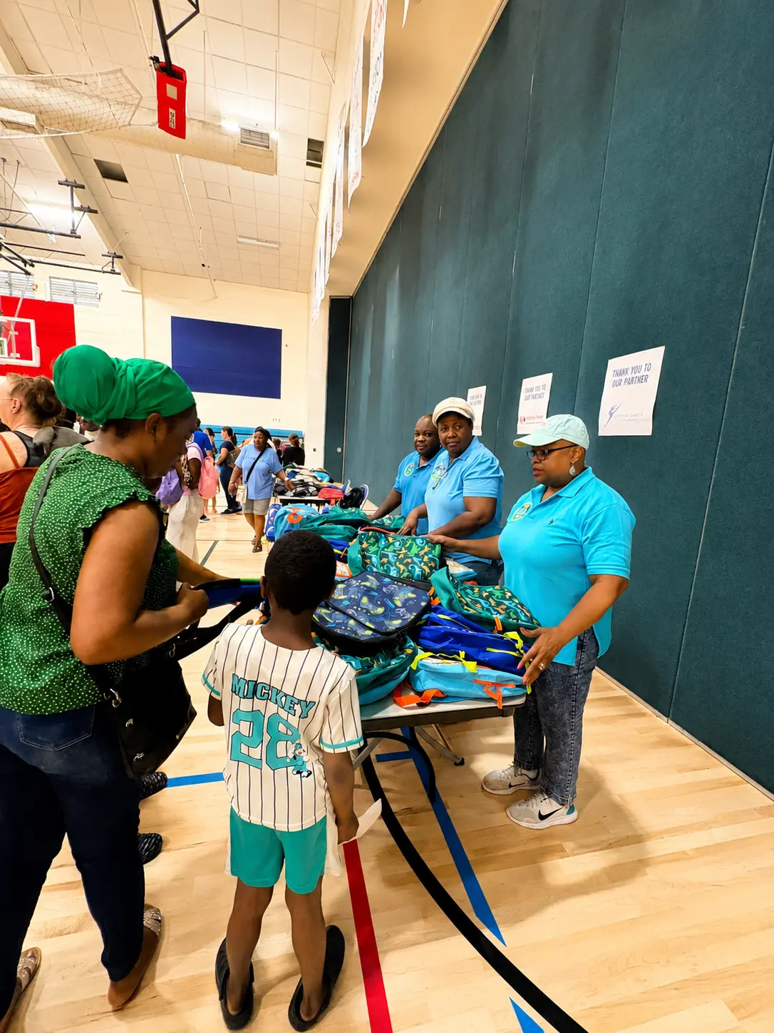 Volunteers handing out backpacks to a parent and child