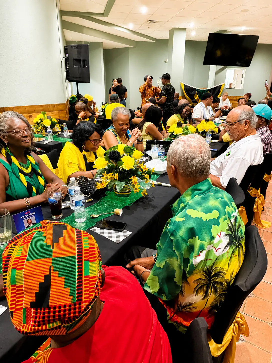 Members in green and gold attire chatting at a banquet table