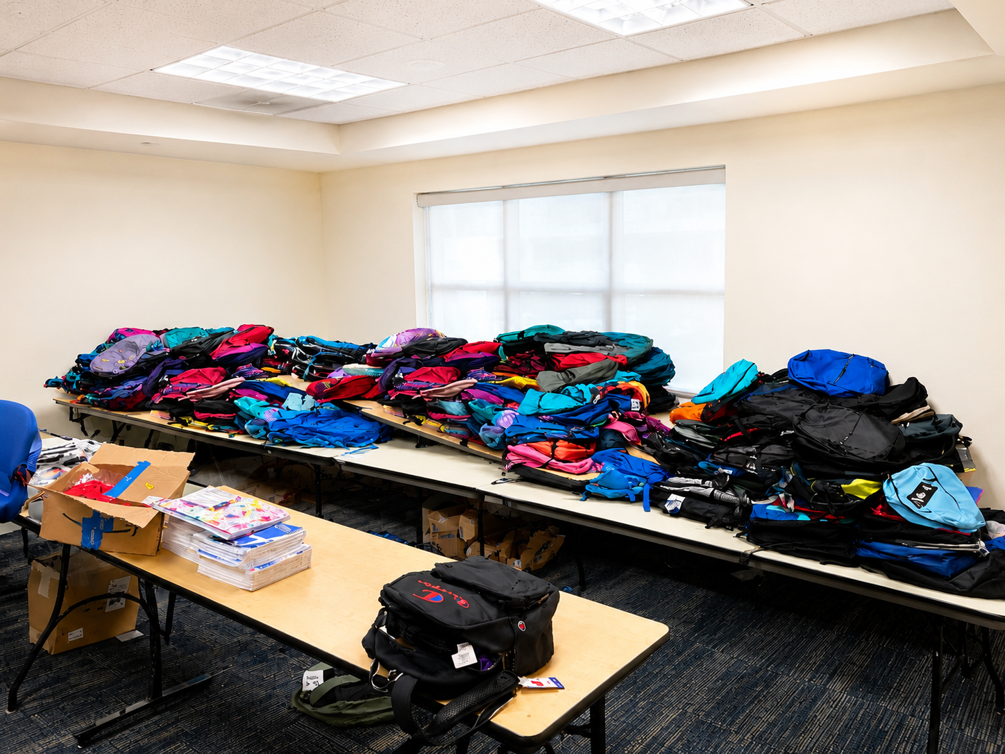 Tables filled with colorful donated backpacks and school supplies